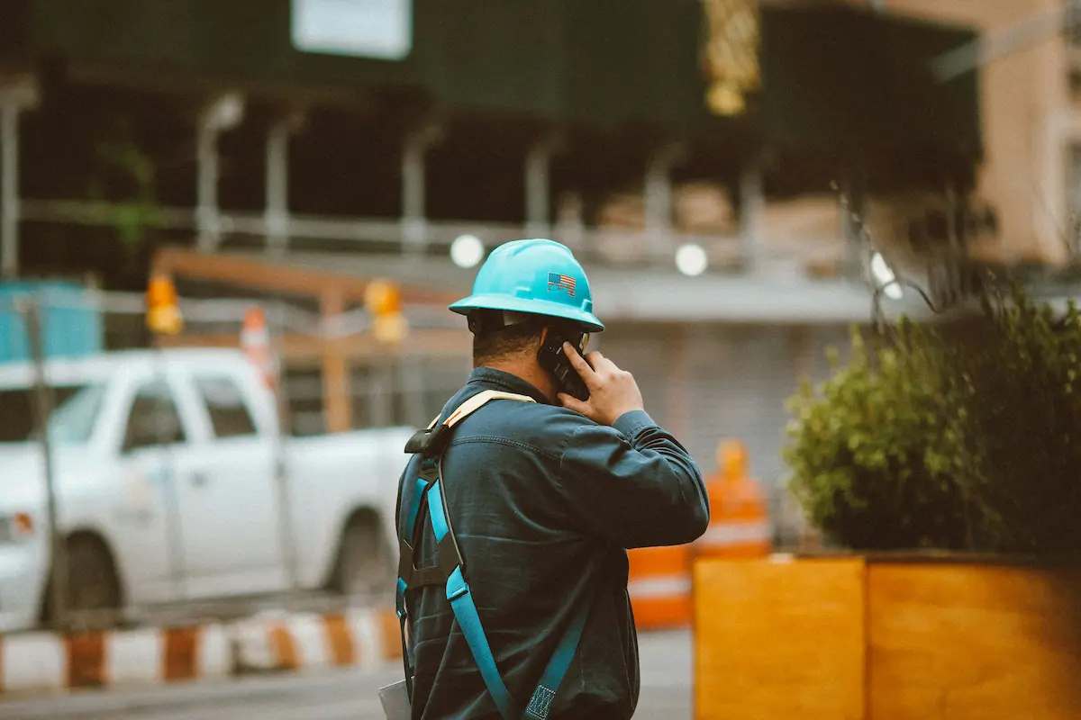 Homme travaillant sur un chantier et tenant un smartphone durci à l'oreille