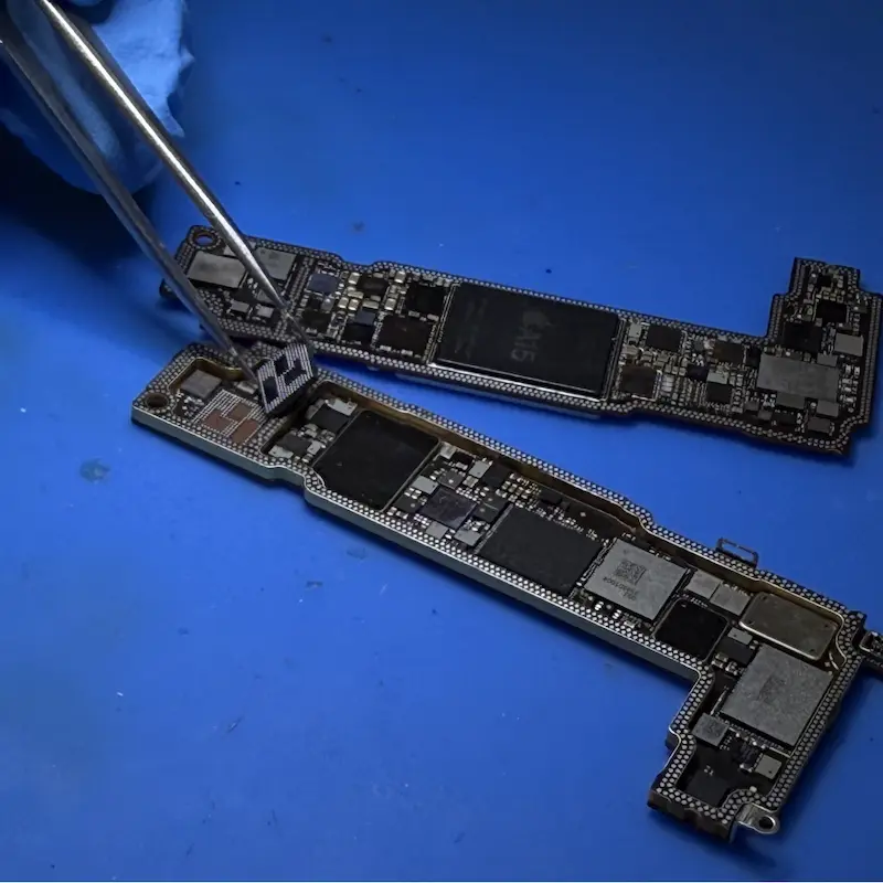Technicien ganté de Leasephone retirant un composant à la pince de précision sur la carte mère d'un iPhone, atelier de Marseille