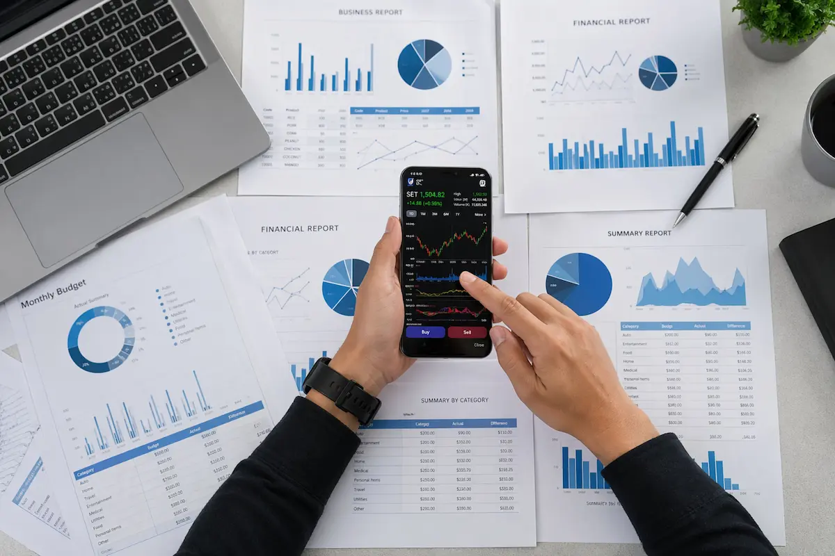Smartphone et feuilles montrant des graphiques et diagrammes sur un bureau